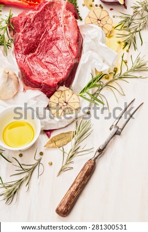 Raw beef meat with oil, spices, meat fork and fresh flavoring on white paper, preparation for cooking or grill