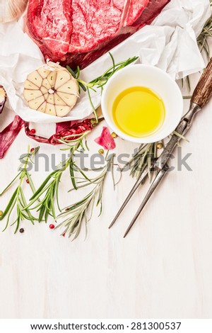 Meat fork, oil and fresh beef meat for cooking, on white wooden background.