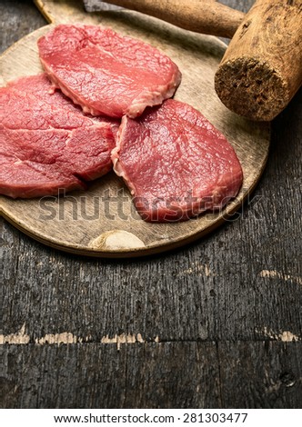 Veal schnitzel preparation on rustic wooden background with old meat hammer