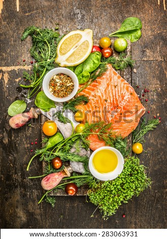 fresh salmon fillet with fresh healthy herbs,vegetables, oil and spices on rustic wooden background, top view
