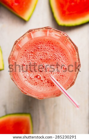 Glass of watermelon smoothie with drink straw, top view, close up