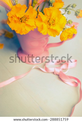 Yellow garden flowers in pink cup and ribbon,  still life, toned