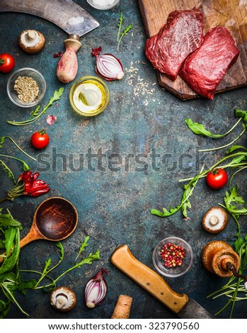 Fresh beef steak, wooden spoon, knife and aromatic herbs, spices and vegetables for cooking , on rustic background, top view, frame.