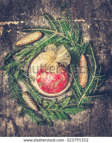 Christmas card with retro ball,  fir branches and cones on dark rustic wooden background, retro toned