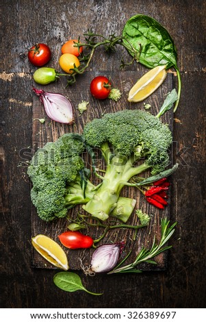 Fresh broccoli and vegetables ingredients and seasoning for tasty vegetarian cooking on rustic wooden background, top view. Diet or vegan food concept.