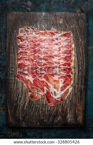 Slices of coppa meat on rustic wooden background. Traditional Italian specialty made from pork neck . Top view