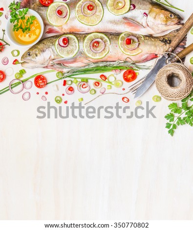 Fresh char with ingredients for fish dishes cooking on white wooden background, top view,border.  Healthy food or diet nutrition concept.