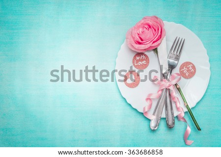 Romantic dinner table place setting with rose and sign decoration on blue background, top view. Valentines day and love concept.