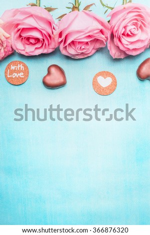 Pink roses with heart chocolate and romantic love message on blue background, top view. Valentine\'s Day or Birthday greeting card