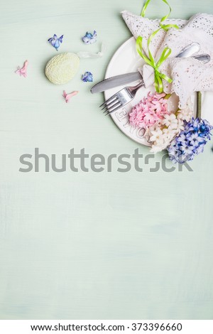 Easter  table setting with plate, cutlery, lace doily napkin,  hyacinths flowers and decor egg on light shabby chic wooden background, top view, vertical