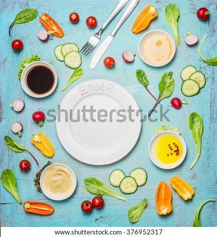 Fresh delicious salad and dressing ingredients around empty white plate on light blue background, top view, frame. Health salad making. Flat lay of healthy  lifestyle or detox diet food  concept