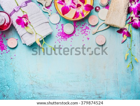 Spa or wellness setting with pink purple orchid flowers , bowl of water, towel, cream , sea salt and nature sponge on turquoise blue background, top view, place for text. Body care concept