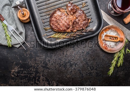 Grilled steak on grill pan with rosemary and spices , dark rustic metal background, top view, place for text, border