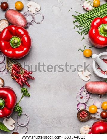 Red paprika and diverse vegetables and cooking ingredients on gray stone background, top view, frame, vertical. Vegetarian food and healthy lifestyle concept.
