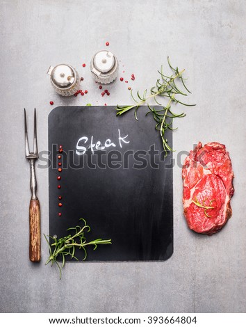 Chalkboard cooking background with raw steak, meat fork, herbs and spices, top view, place for text. Meat food