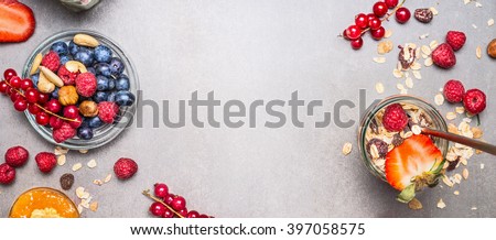 Muesli, nuts and berries. Breakfast preparation. Granola with fresh berries in jar on stone background, top view, banner.  Healthy food and Clean Eating concept