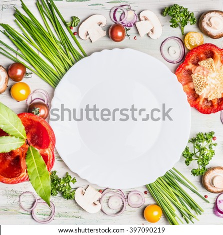 Fresh organic vegetables and seasoning ingredients for tasty vegetarian cooking around blank white plate , top view. Healthy or diet food concept.