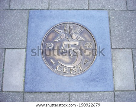 Image of former Dutch five cents coin cemented in sidewalk