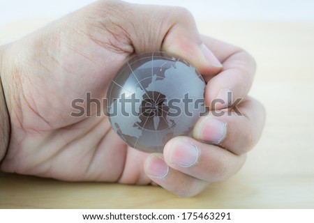 Glass the world in hand on wooden background