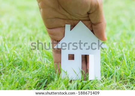 concept image of make house with white paper cut on green grass background