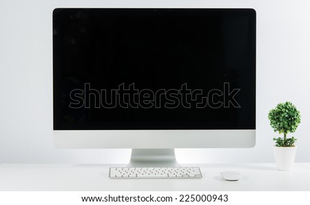 Business place of work with with computer monitor keyboard and jardiniere on white wall