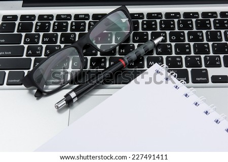 Blank business laptop, mouse, pen and glasses on white table
