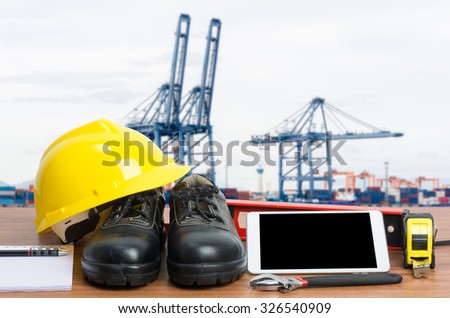 Working table engineer with tablet and tools in cargo port with crane