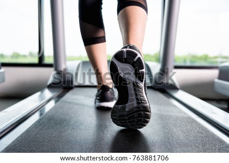 Close up  shoes woman\'s muscular legs feet running on treadmill workout at fitness gym