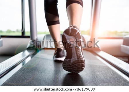 Close up sneakers Fitness girl running on treadmill, Woman with muscular legs in gym