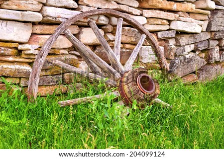 Broken wagon wheel leaning against a century old rock wall. Fayette State Park. Garden, Peninsula.