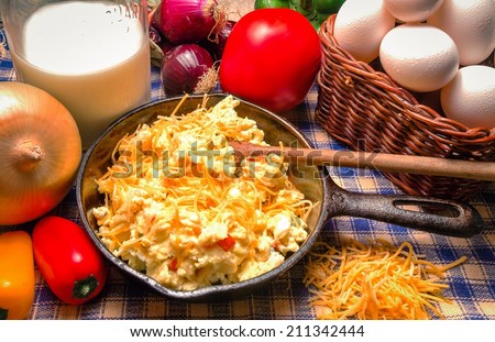 Cast iron skillet with western style scrambled eggs. Including onions, red peppers, cheese and tomato.