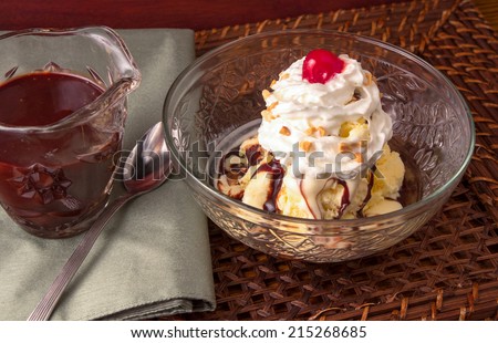 Hot fudge sundae with homemade ice cream and a small carafe with hot fudge.