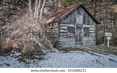 Historical Pioneer Log Cabin. Small historical log cabin in the woods surrounded by snow. This is not a privately owned residence, it is located in a historical village as a public display.