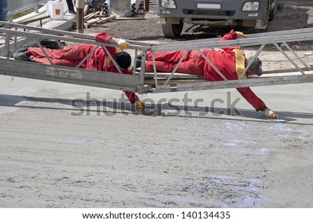 Two construction workers leveling freshly poured concrete mix