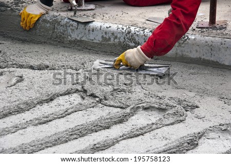 Close up, construction worker spreading concrete with trowel
