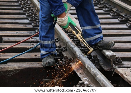 Welder using cutting torch to cut a rail