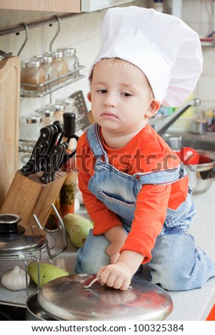 amusing kid in a chef cap on kitchen