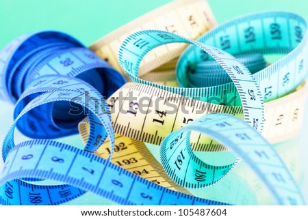 Yellow, green and dark blue measuring tapes on a green background