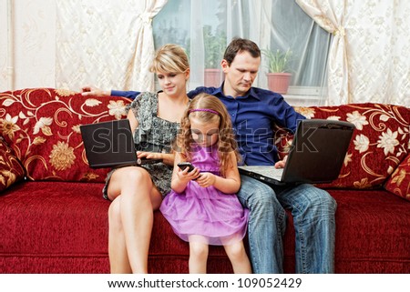 Family of three people sitting on the couch, each with their own personal computer
