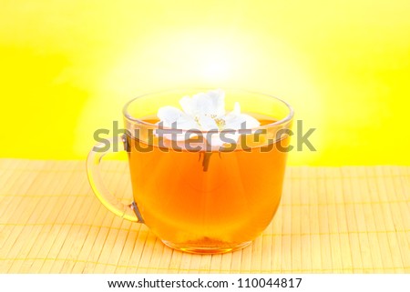 Hot tea with a jasmine flower a yellow background