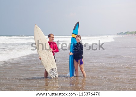Young people with surfboards stand in water