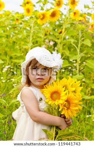 Little girl with a big bouquet of sunflowers in the field