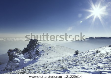 Beautiful landscape with snow-covered mountains, the sun and clouds