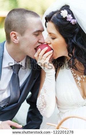 groom and the bride together eat a ripe peach