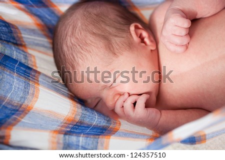 sleeping newborn kid on a checkered sheet