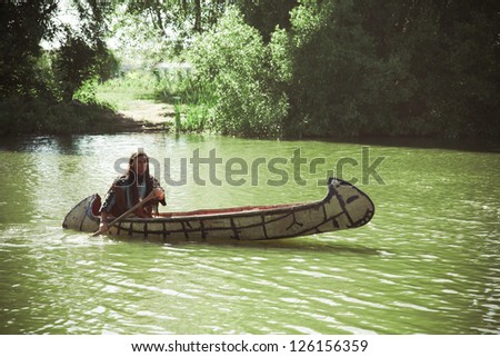 North American Indian floats down the river on a canoe