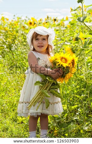 little girl with a big bouquet of sunflowers in the field