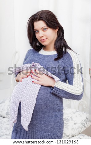 pregnant woman holds a children\'s romper suit