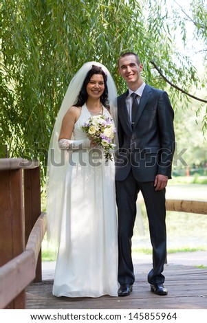 groom and the bride cost on the wooden bridge in a summer garden