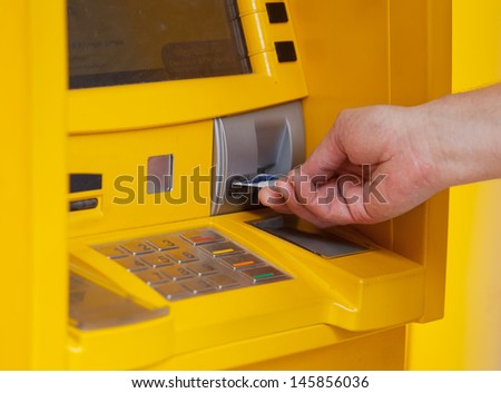 man inserts a plastic card into the ATM